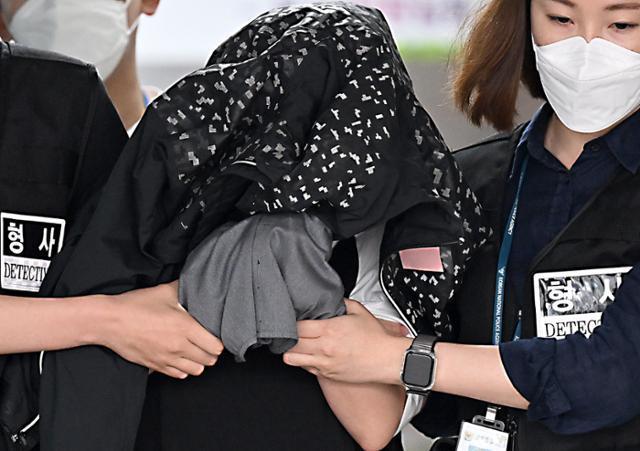 The mother, who was arrested on charges of killing her two infants and storing their bodies in a refrigerator for several years, is transferred to the prosecution from Suwon Nambu Police Station in Gyeonggi Province on June 30, 2023. / Korea Times file